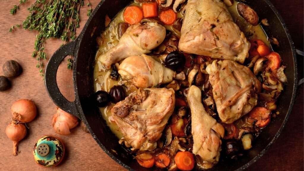 A rustic dish of Coq au Vin, featuring braised chicken in a rich red wine sauce, garnished with fresh herbs.